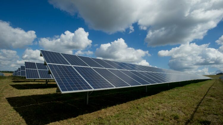 Solar panels in a field under a cloudy sky.