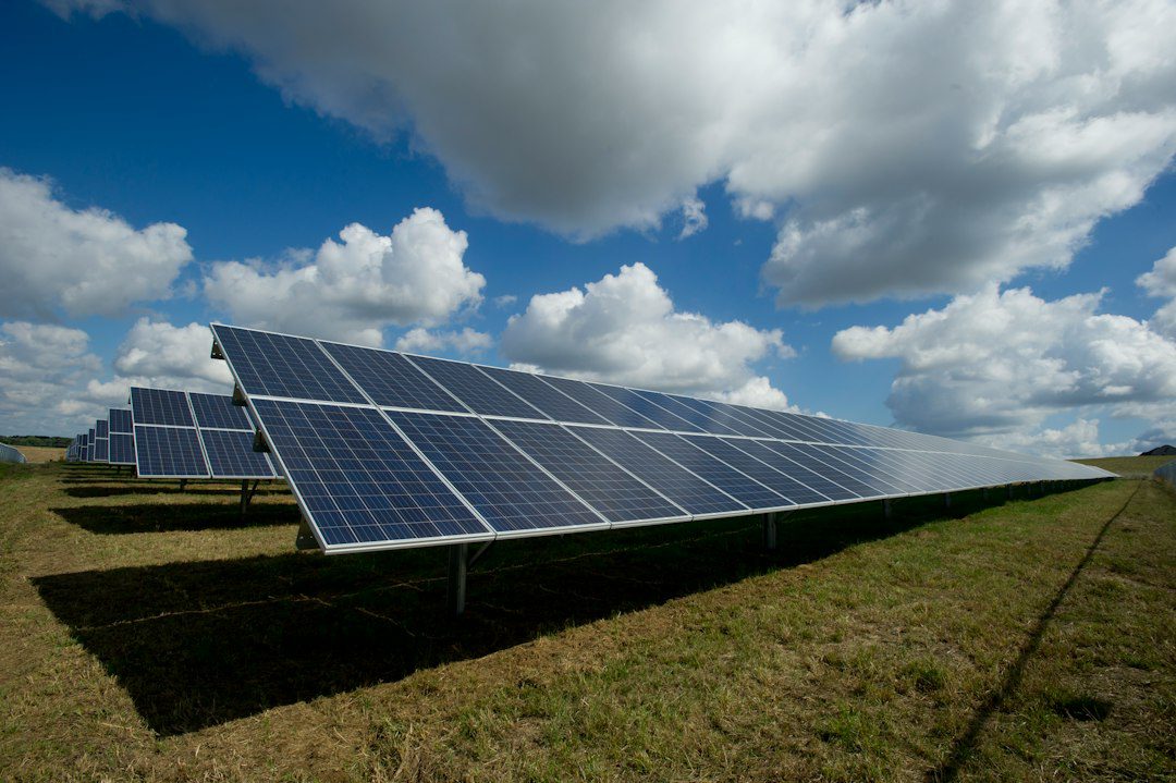 Solar panels in a field under a cloudy sky.